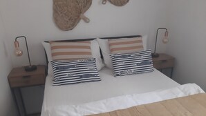 A neatly made bed with striped pillows, a bedside lamp, and a book on a wooden table. - Naturally happy (170m to the Müritz) (Röbel/Müritz)