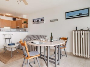 Eine moderne Küche mit Holzschränken, einem Essbereich mit rundem Tisch und Stühlen, einem gestreiften Sofa und einem Heizkörper.