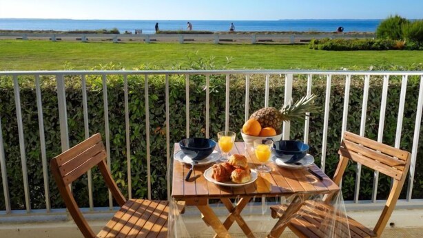 Un balcon avec une table préparée pour le petit-déjeuner, donnant sur une plage.