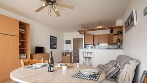 Une cuisine moderne avec des meubles en bois, une table à manger avec une bouteille de vin et un canapé.