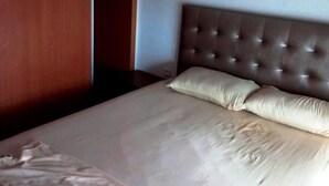 Ein ordentlich bezogenes Bett mit einer karottenförmigen Kopfstütze und zwei Kissen.