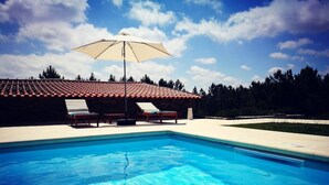 A swimming pool with clear blue water, surrounded by lounge chairs and an umbrella. - Quinta dos Morangueiros, Douro Valley (Armamar)