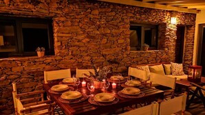 A stone-walled dining area with a wooden table set for six, surrounded by chairs. - Quinta dos Morangueiros, Douro Valley (Armamar)