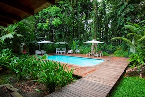 Una piscina al aire libre, sombrillas, tumbonas