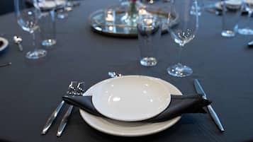 A table set with a white plate, black napkin, and silverware.