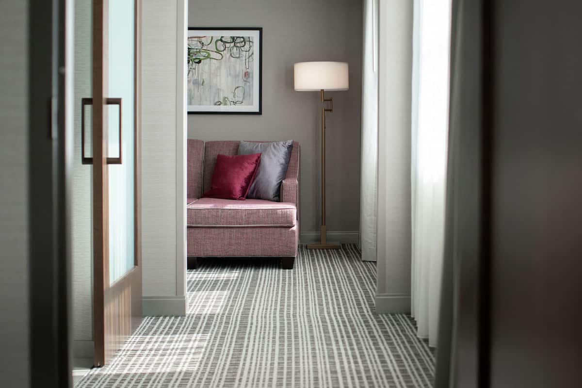 A hallway with a patterned floor, a sofa with cushions, a floor lamp, and a framed artwork on the wall.