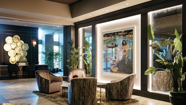 A modern lobby with a large pool view, comfortable seating, and large windows. - The Axis Moline Hotel, Tapestry Collection by Hilton (Moline)