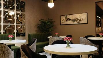A modern interior with round tables, green upholstered seating, and decorative wall art.