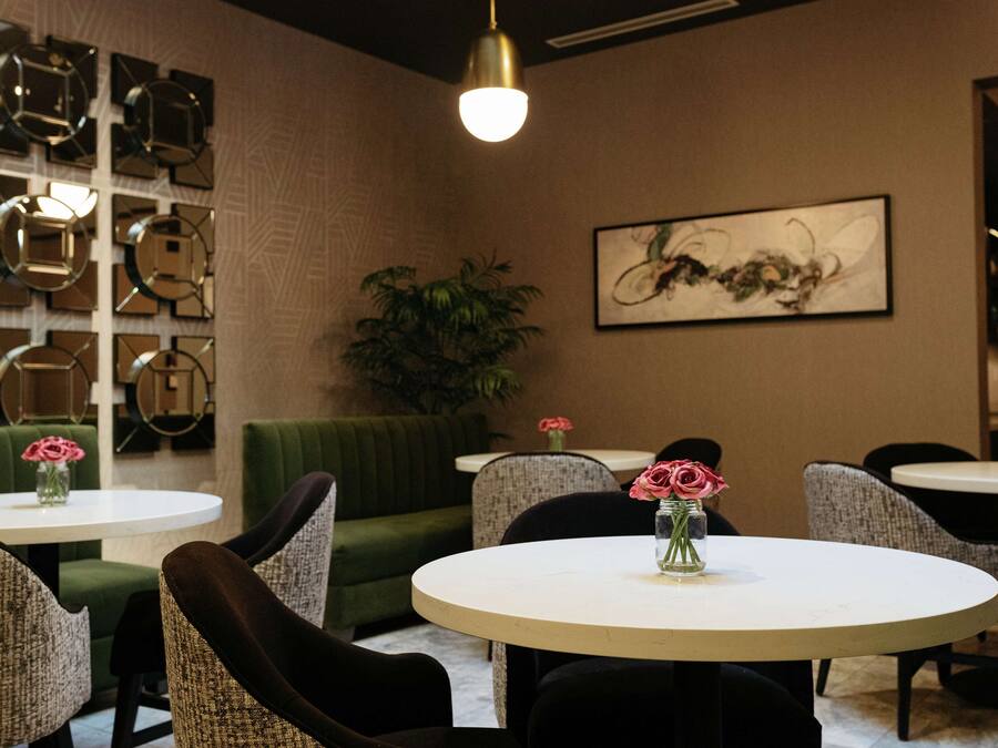 A modern interior with round tables, green upholstered seating, and decorative wall art.