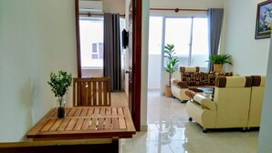 A living room with a wooden dining table and chairs, a sofa set, and a potted plant. - Hidden from the noise (Tp. Vũng Tàu)