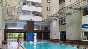 An indoor swimming pool with a tiled floor, a central pillar, and a covered upper level with balconies. - Hidden from the noise (Tp. Vũng Tàu)