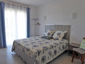 A bedroom with a bed, a bedside table, a chair, and a wardrobe.