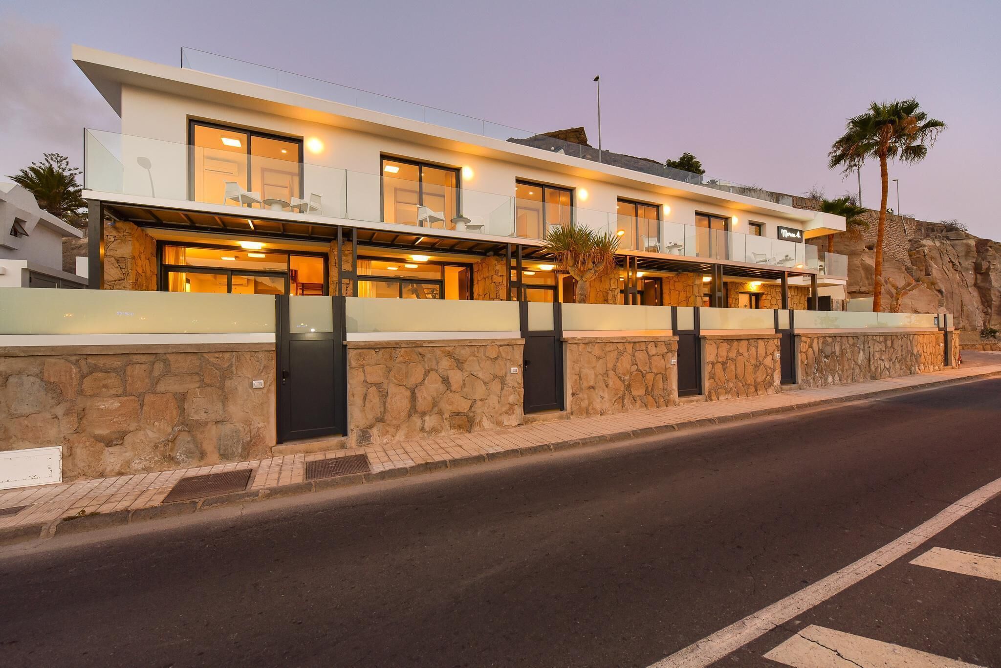 A modern hotel with a stone facade, multiple balconies, and a restaurant area.