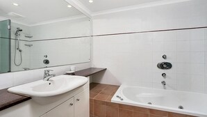 A modern bathroom with a white sink, a large mirror, a bathtub, and a shower area. - Cremorne - HAMP1 - Hampden Avenue - Bright 1BR with Sunroom, Balcony Garage Near Neutral Bay Shops (Cremorne)
