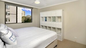 A bedroom with a bed, a ceiling fan, a window with blinds, and a built-in wardrobe. - Cremorne - HAMP1 - Hampden Avenue - Bright 1BR with Sunroom, Balcony Garage Near Neutral Bay Shops (Cremorne)