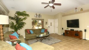 A living room with a ceiling fan, a television, a sofa set, a coffee table, and a potted plant. - Poolside Panorama- Perfect Lake view (Lake Havasu City)