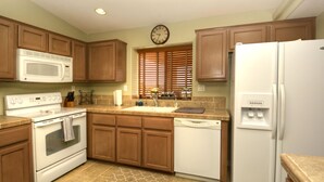 A kitchen with wooden cabinets, a microwave, stove, sink, dishwasher, and a refrigerator. - Poolside Panorama- Perfect Lake view (Lake Havasu City)