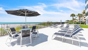 Eine Terrasse mit Sitzgelegenheiten, einem Tisch und einem Sonnenschirm.