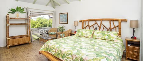 A bedroom with a bed, a ceiling fan, a window, a chair, a table, and a shelf with a plant.