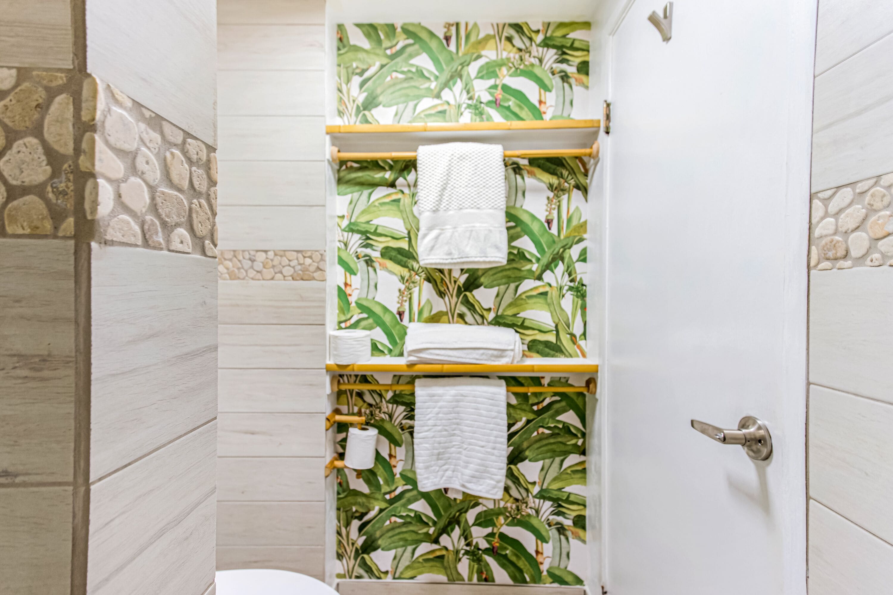 A bathroom with a shower, a toilet, and a towel rack with towels.
