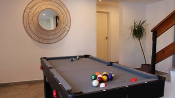 A pool table with balls, a mirror, and a staircase.