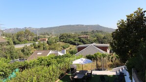 Une terrasse avec une table et des chaises, entourée de verdure et offrant une vue sur un paysage vallonné.