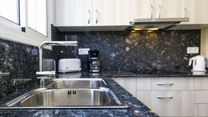 Een moderne keuken met een spoelbak van roestvrij staal, een koffiezetapparaat en een broodrooster op het aanrecht.