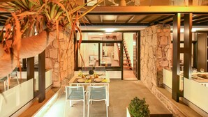 A modern dining area with a stone accent wall, a table set for four, and a view into the adjacent living space. - Morea Suites 3 by VillaGranCanaria (Puerto Rico)