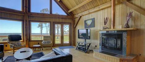 A spacious living room with a fireplace, large windows, and a cozy seating area.