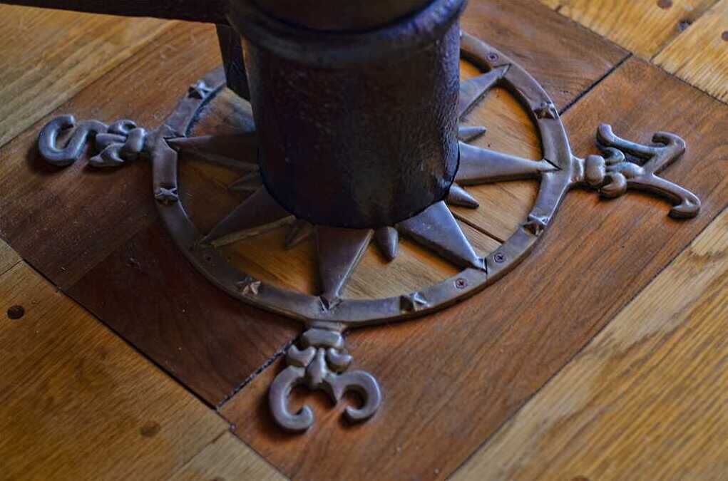A compass-like object with a central pole and directional arms on a wooden surface.