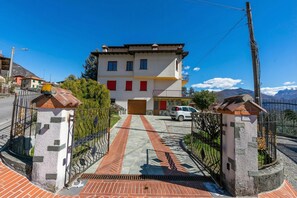 A two-story building with a red door, a paved driveway, and a gated entrance. - Il Panorama di Forster, Menaggio, Italy (Menaggio)