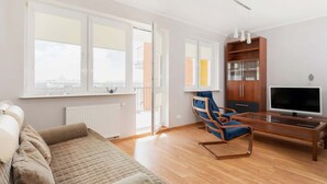 Una sala moderna con un sofá, una mesa de centro de vidrio, un televisor y un mueble de madera.