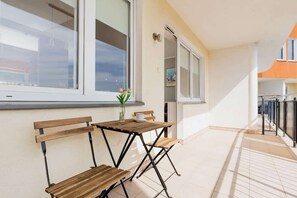 Un couloir avec un banc en bois, une petite table sur laquelle est posé un vase, et une fenêtre.