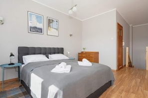 Une chambre à coucher avec un lit, une table de chevet, une commode et deux tableaux encadrés accrochés au mur.