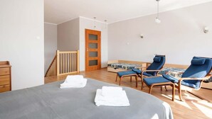 Un dormitorio con una cama, dos sillas azules, un escritorio de madera y una puerta.