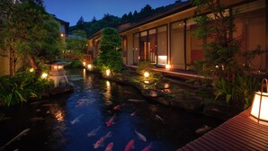 Un estanque tranquilo con carpas, un muelle de madera y arquitectura japonesa tradicional, incluyendo un farol y una pagoda.