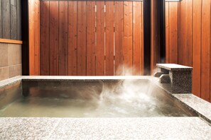 A hot spring bath with a wooden backdrop and stone seating. - Ryokusuitei (Kamogawa)