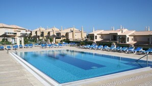 Una piscina con sillones de descanso y una zona de terraza con baldosas.