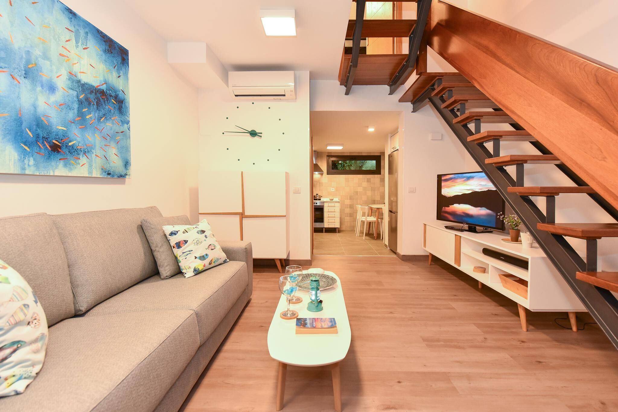 Un saló modern amb un sofà, una taula de centre i obres d'art. Una escala condueix a un nivell superior.