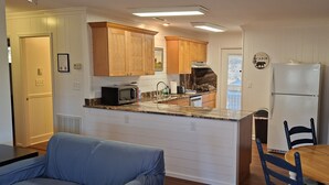 Una cocina compacta con armarios de madera, un microondas integrado y un refrigerador.