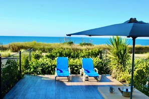 A patio with two blue lounge chairs, a table with a teapot and a mug, and a view of the ocean. - SEAFRONT, Fantastic 180° Sea View, High Standard, Garden and Private Parking (Barneville Carteret)