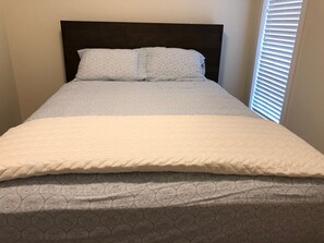 Cozy retreat with a neatly made bed, white quilt, and patterned duvet.