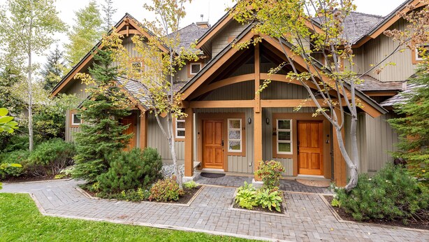 A log cabin-style building with a prominent front porch, multiple doors, and a landscaped front yard.