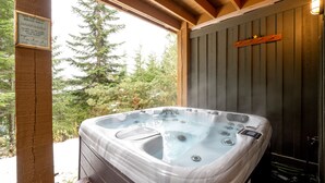 A hot tub in a wooden cabin with a sign advising against sitting on the cover.