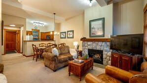 A living room with a fireplace, a television, and a dining area with wooden furniture.