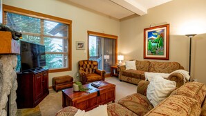 A living room with a television, two sofas, a coffee table, and a fireplace.