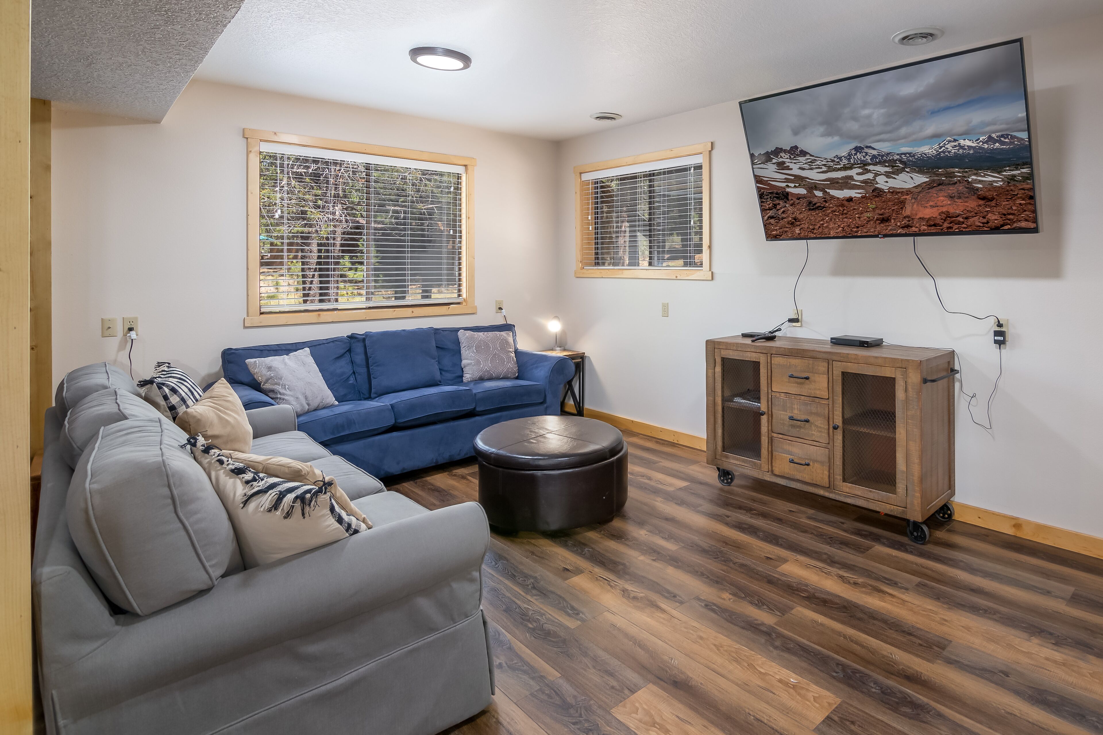 Una sala de estar con un sofá azul, un sofá gris y un mueble de madera.