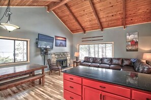 A spacious living area with a wooden ceiling, a fireplace, a large window, and a red kitchen island.