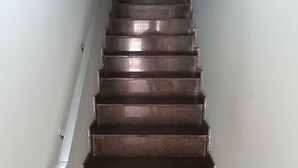 Una scala con corrimano a sinistra e una porta in cima.