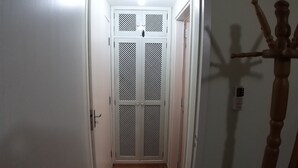 Un corridoio stretto con una porta bianca decorata con un motivo a reticolo.